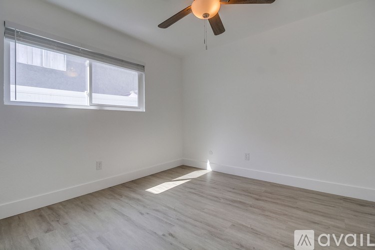 A room with a ceiling fan and a window letting in sunlight.
