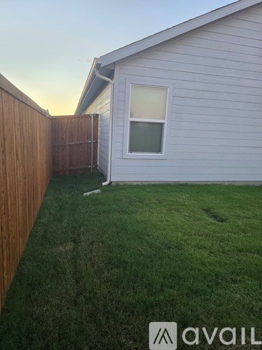 A backyard with a wooden fence and a house.