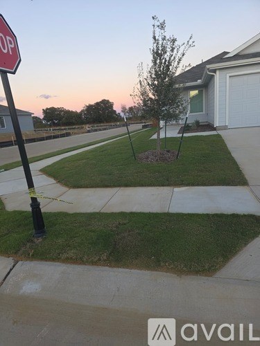 A stop sign is on a pole at the edge of a sidewalk.