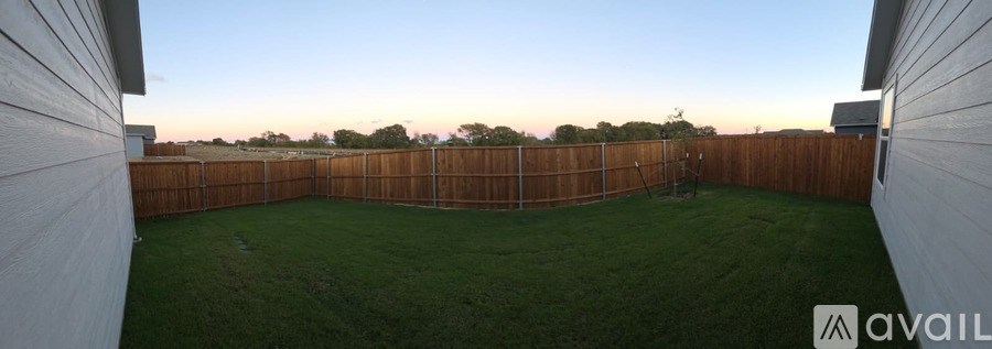 A backyard with a wooden fence and green grass.