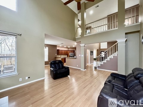A living room with a black leather couch and wooden floors.