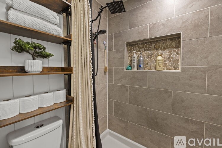 A bathroom with a shower, toiletries, and a plant.