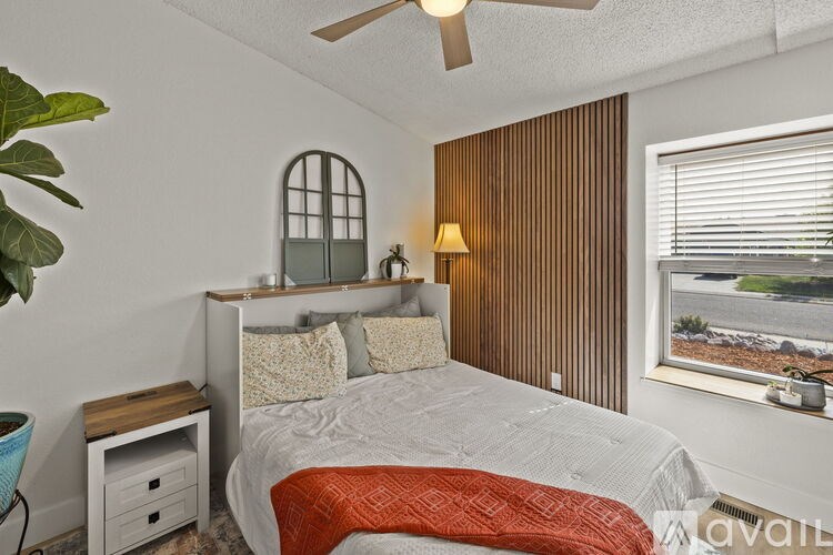 A bedroom with a bed, a window, and a ceiling fan.
