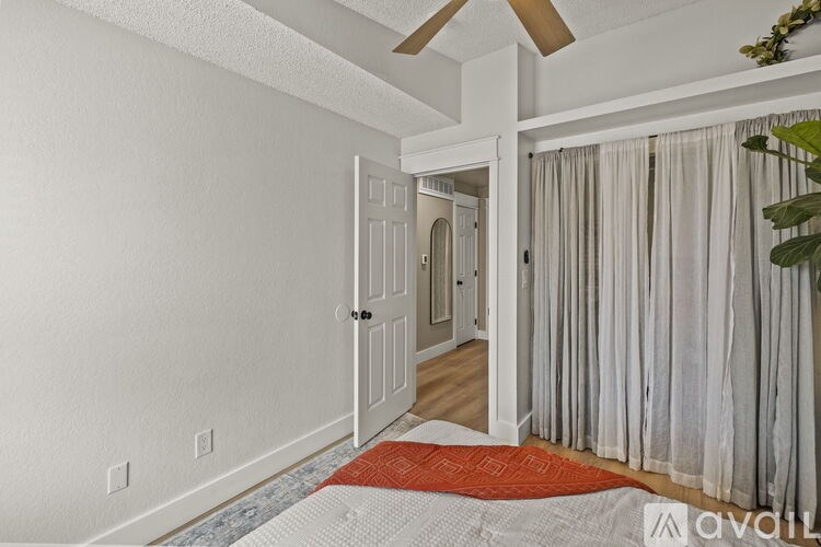 A bedroom with a bed, a ceiling fan, and a door leading to another room.