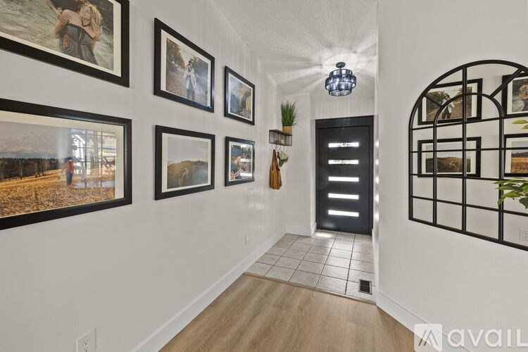 A hallway with a series of framed pictures on the wall and a black door at the end.