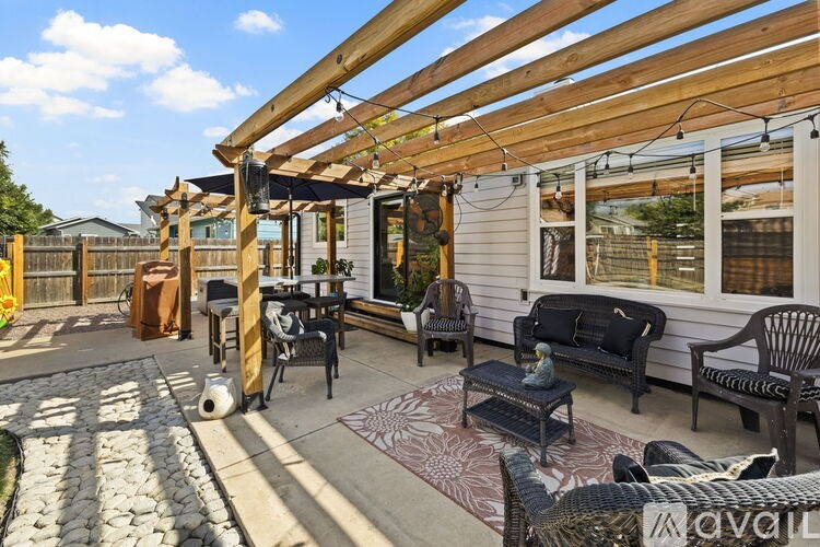 A patio with a table and chairs under a wooden pergola.