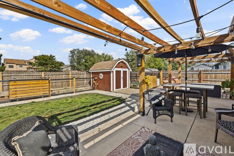 A backyard with a wooden pergola and patio furniture.