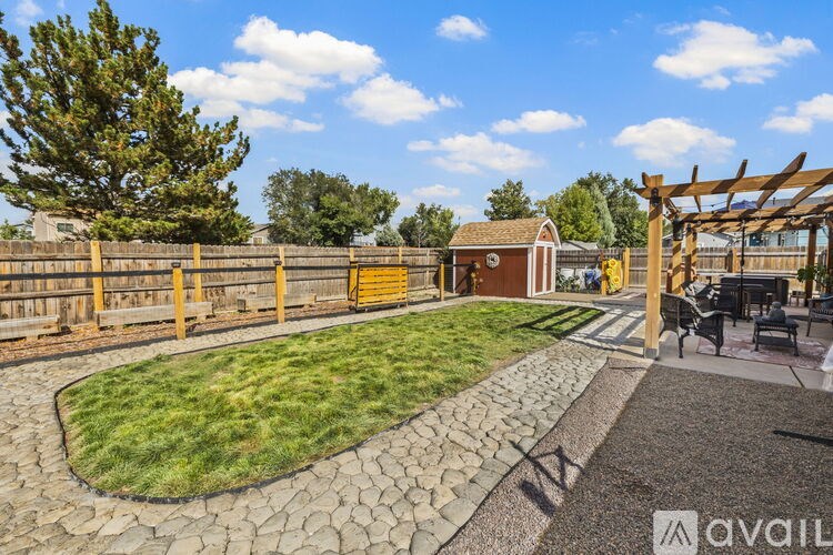 A backyard with a stone patio and a wooden pergola.