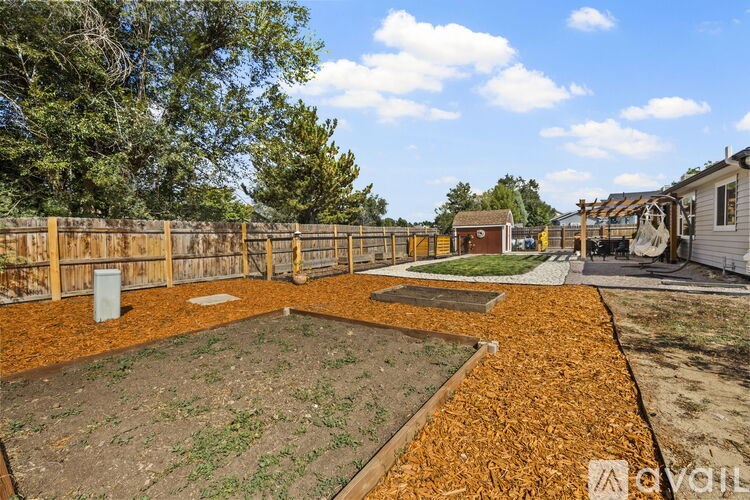 A backyard with a fence, a small garden, and a shed.
