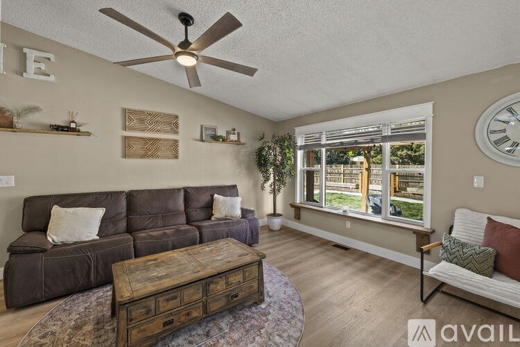 A living room with a brown leather couch, a wooden coffee table, and a ceiling fan.