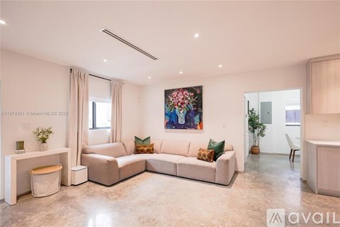 A living room with a white sofa, a white side table, and a painting on the wall.