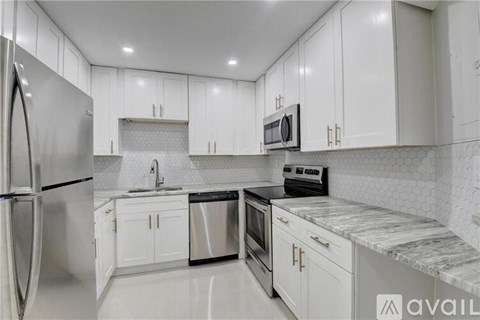 A kitchen with white cabinets and a marble countertop.
