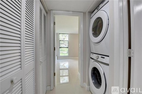 A white washing machine is in a narrow hallway.