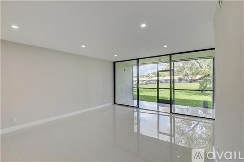 A spacious room with large windows overlooking a green landscape.