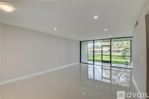 A spacious room with a large window overlooking a green outdoor area.