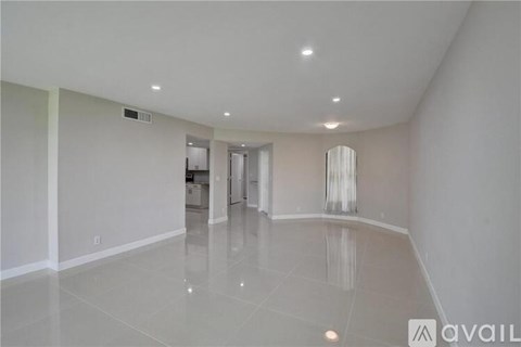 A spacious room with a white floor and ceiling, and a doorway leading to another room.