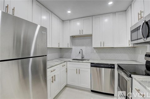 A modern kitchen with white cabinets and stainless steel appliances.