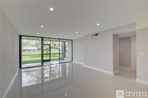 A spacious room with a large window and a view of a green lawn outside.