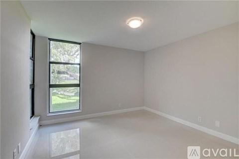 A room with a window and a view of a lawn and trees outside.