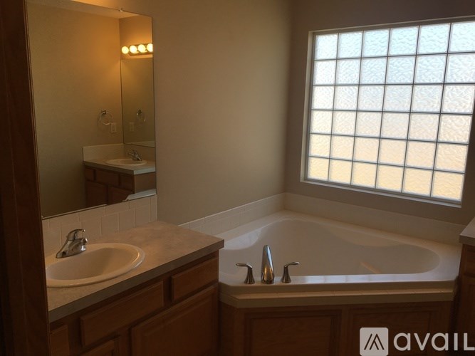 A bathroom with a tub, sink, and mirror.