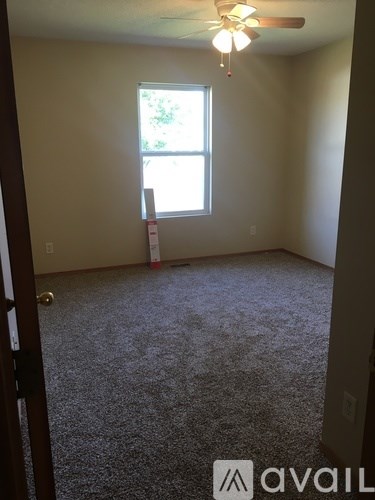 A room with a carpeted floor and a ceiling fan.