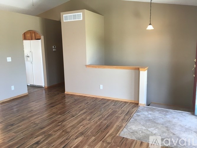 A room with wooden flooring and a white refrigerator.