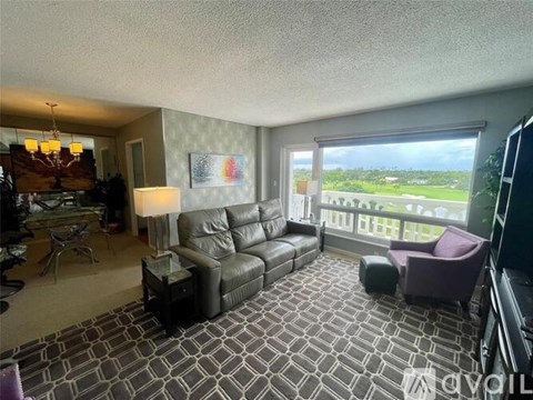 A living room with a large couch and a balcony with a view of the outside.