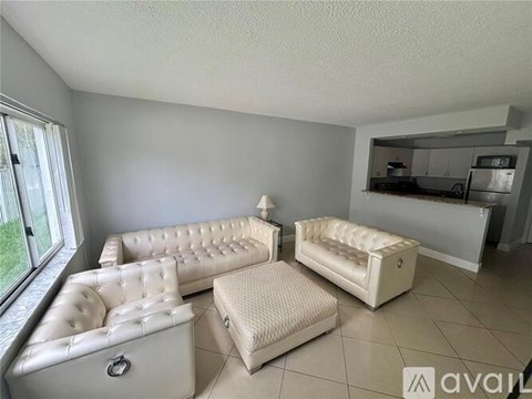 A living room with a white couch and ottoman.