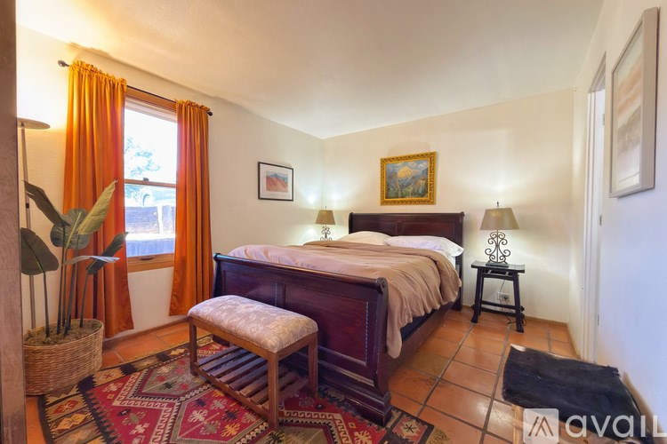 A bedroom with a bed, a bench, and a potted plant.