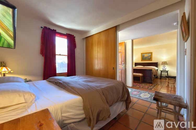 A bedroom with two beds and a chair in front of a window.