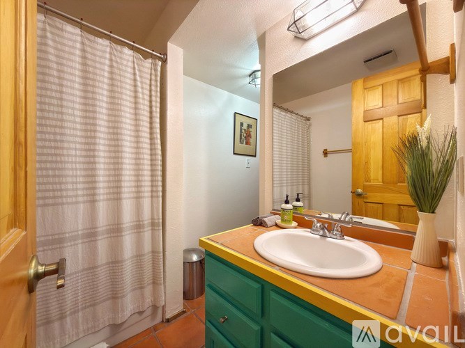 A bathroom with a green vanity and a white sink.