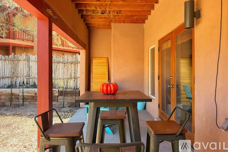 A table with a pumpkin on it sits on a porch.