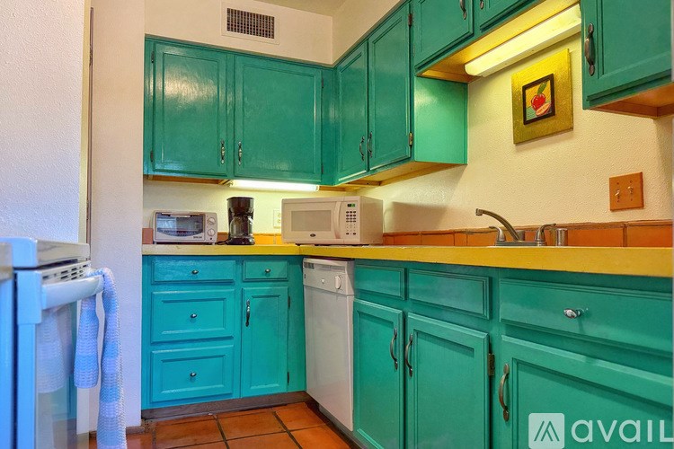 A kitchen with teal cabinets and a yellow counter.