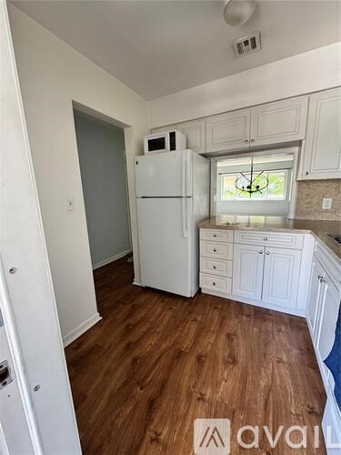 A kitchen with a white fridge and wooden floors.