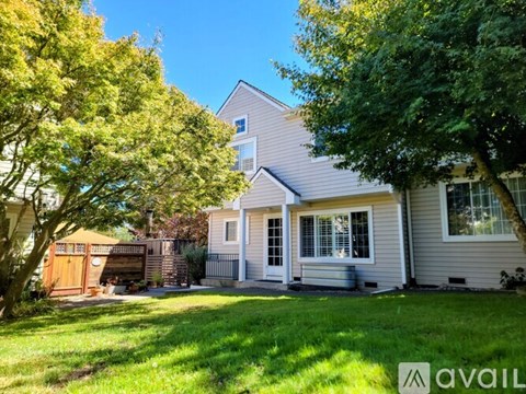 A house with a well-kept lawn and trees in the front yard.