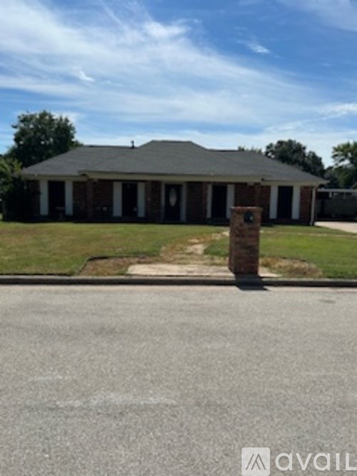 A house with a grey roof and a brick pillar in front.