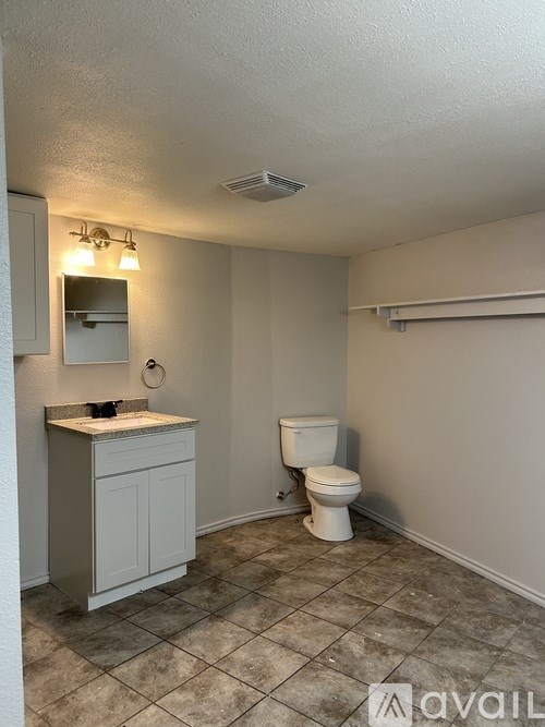 A bathroom with a toilet, sink, and mirror.