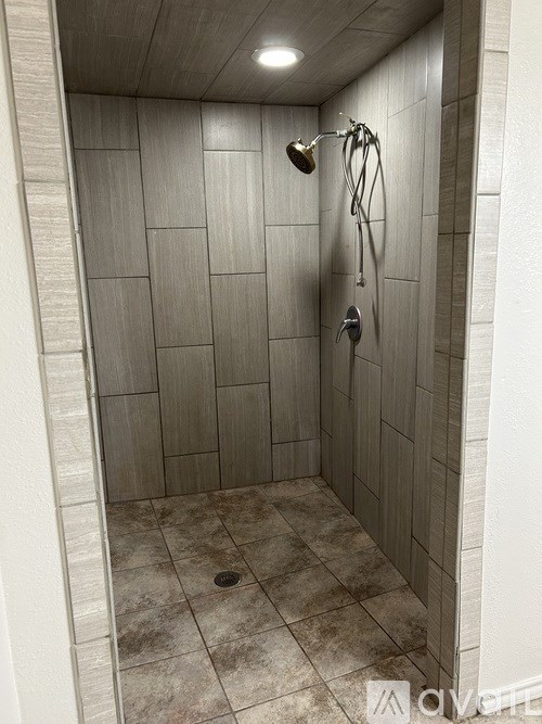 A shower area with a tiled wall and floor.