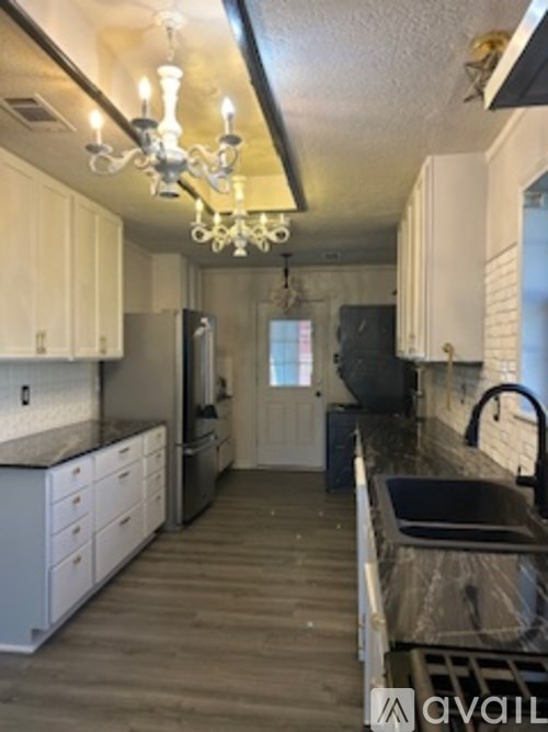 A kitchen with white cabinets and a chandelier.
