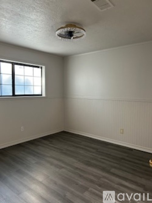 A room with a window and wooden flooring.
