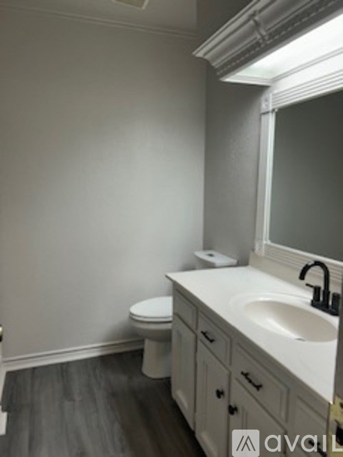 A bathroom with a toilet, sink, and mirror.