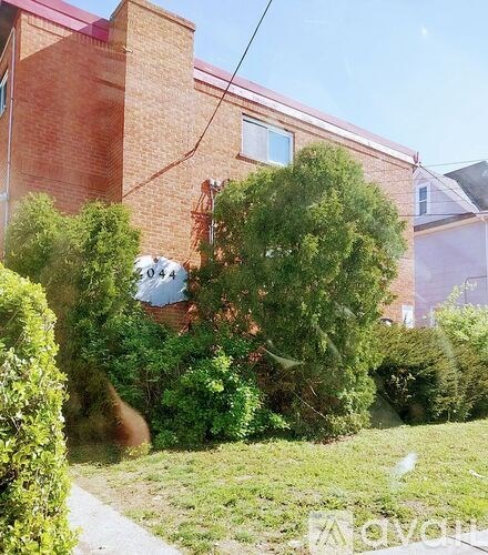A red brick house with a tree in front of it.