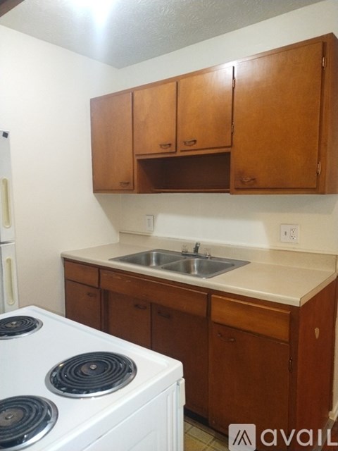 A kitchen with a white stove and wooden cabinets.