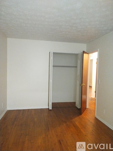 A room with a wooden floor and a white wall with a door.