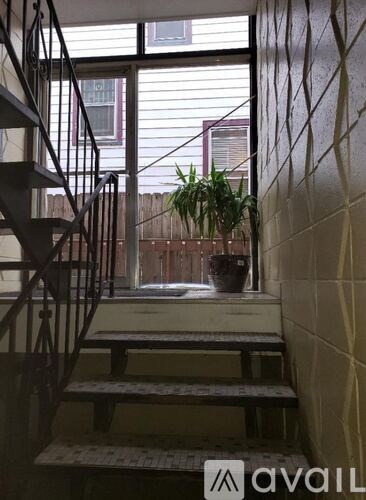 A staircase with a metal railing and a potted plant on a windowsill.