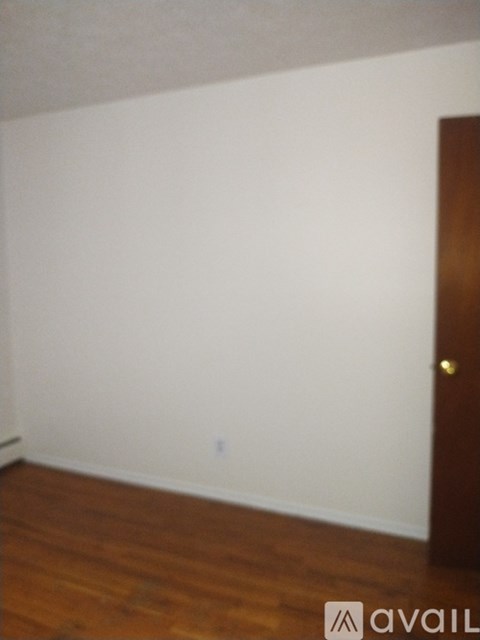 A room with a wooden floor and a white wall.