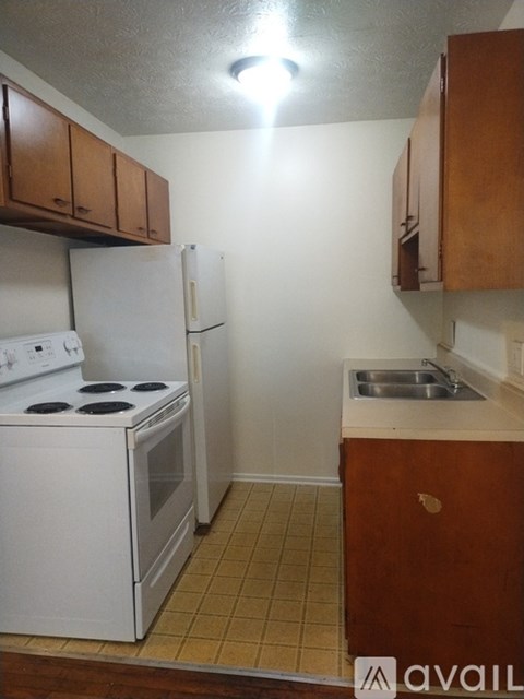 A small kitchen with white appliances and wooden cabinets.
