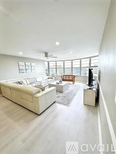 A spacious living room with a white sofa and a wooden chair.