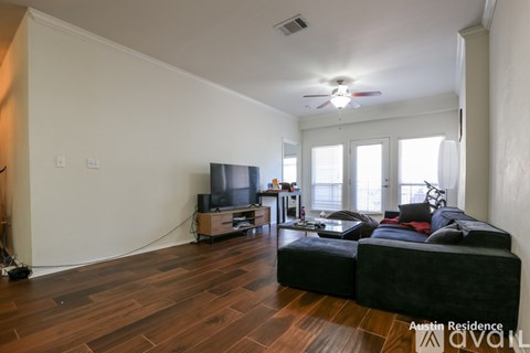 A living room with a black couch and wooden floors.