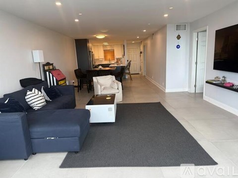 A living room with a blue couch and a grey rug.